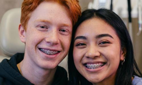 Deux jeunes patients souriants portant des appareils dentaires orthodontiques au cabinet du Dr Wees.