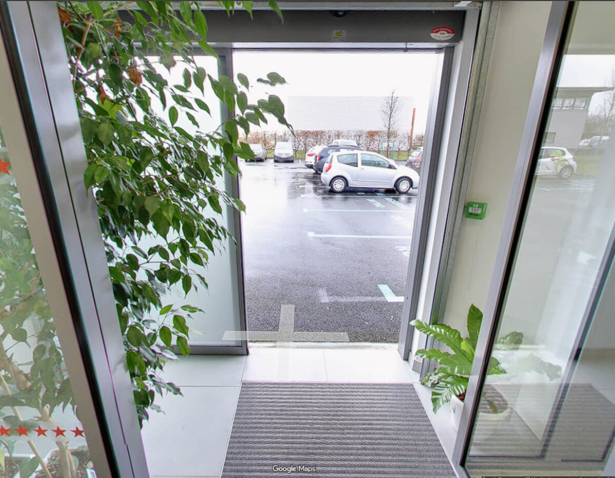 Entrée principale du cabinet d'orthodontie du Dr Wees à Caen avec plantes et vue sur le parking