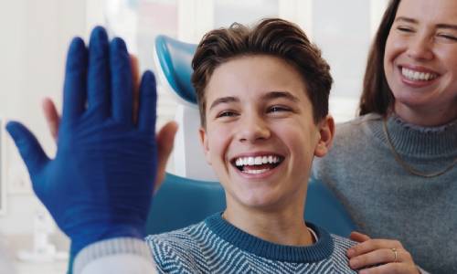 Un jeune adolescent sourit en faisant un tape-main avec son orthodontiste au cabinet à Caen.